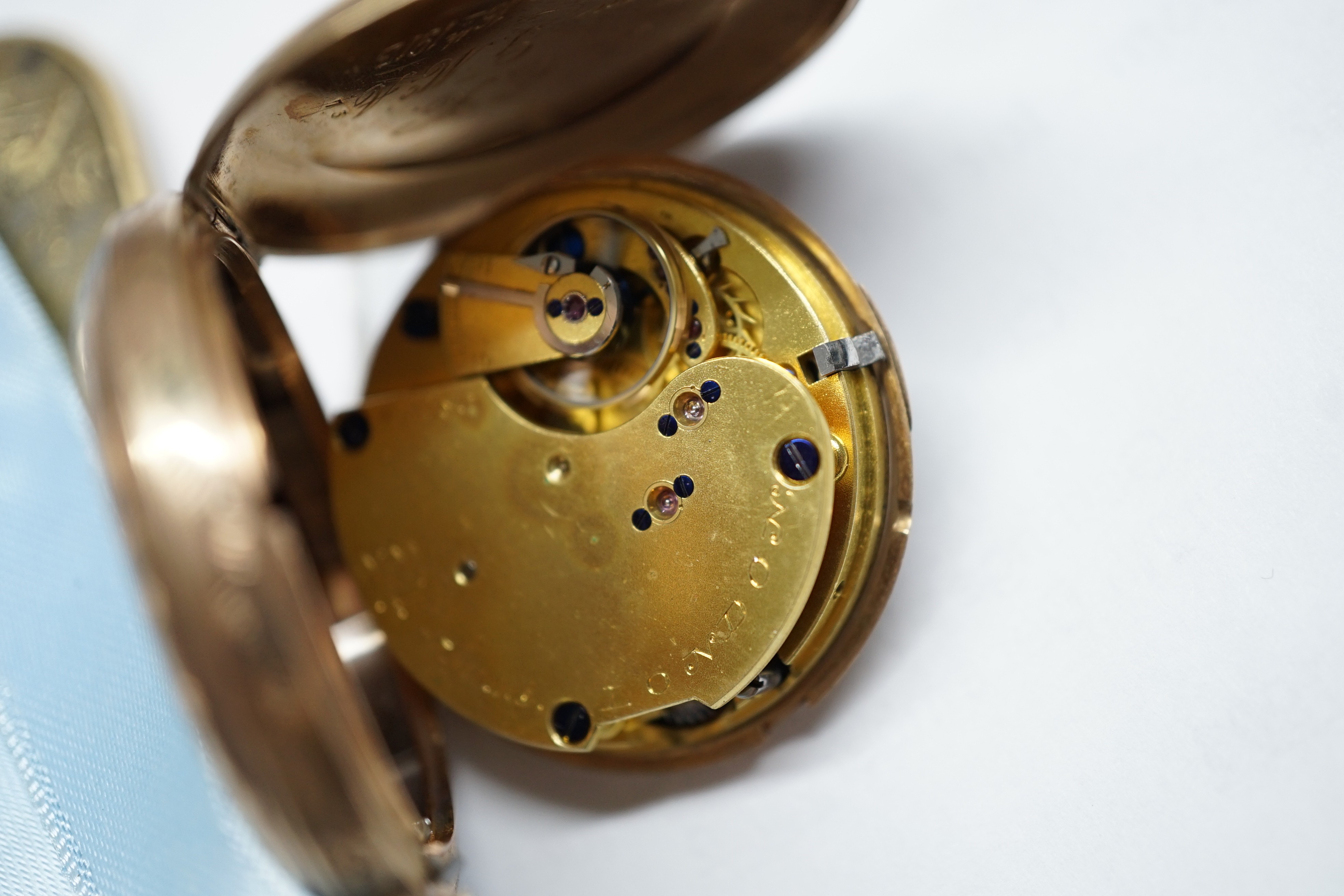 An early 20th century engraved 9ct gold hunter fob watch, with Roman dial, gross 36.7 grams, on a blue sash with yellow metal mounted hardstone fob.